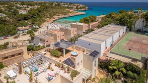 A coastal residential area with multiple buildings, a beach, and a tennis court.