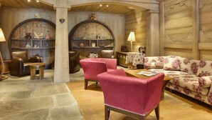 Une pièce chaleureuse aux murs et au plafond en bois, comprenant un canapé, des fauteuils et une table.