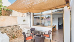 An outdoor patio with a table and chairs, a large umbrella, and a view into the house. - Sa Rossa by Interhome (Llombards/C.Llombards/C.S'Almonia)