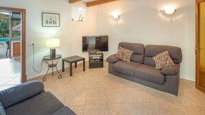 A living room with a sofa, a television, and a lamp. There is a wooden ceiling and a door on the right. - Sa Rossa by Interhome (Llombards/C.Llombards/C.S'Almonia)