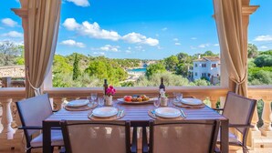 A table set for two with a scenic view of a coastal landscape, including a beach and buildings. - Vista Playa by Interhome (Llombards/C.Llombards/C.S'Almonia)