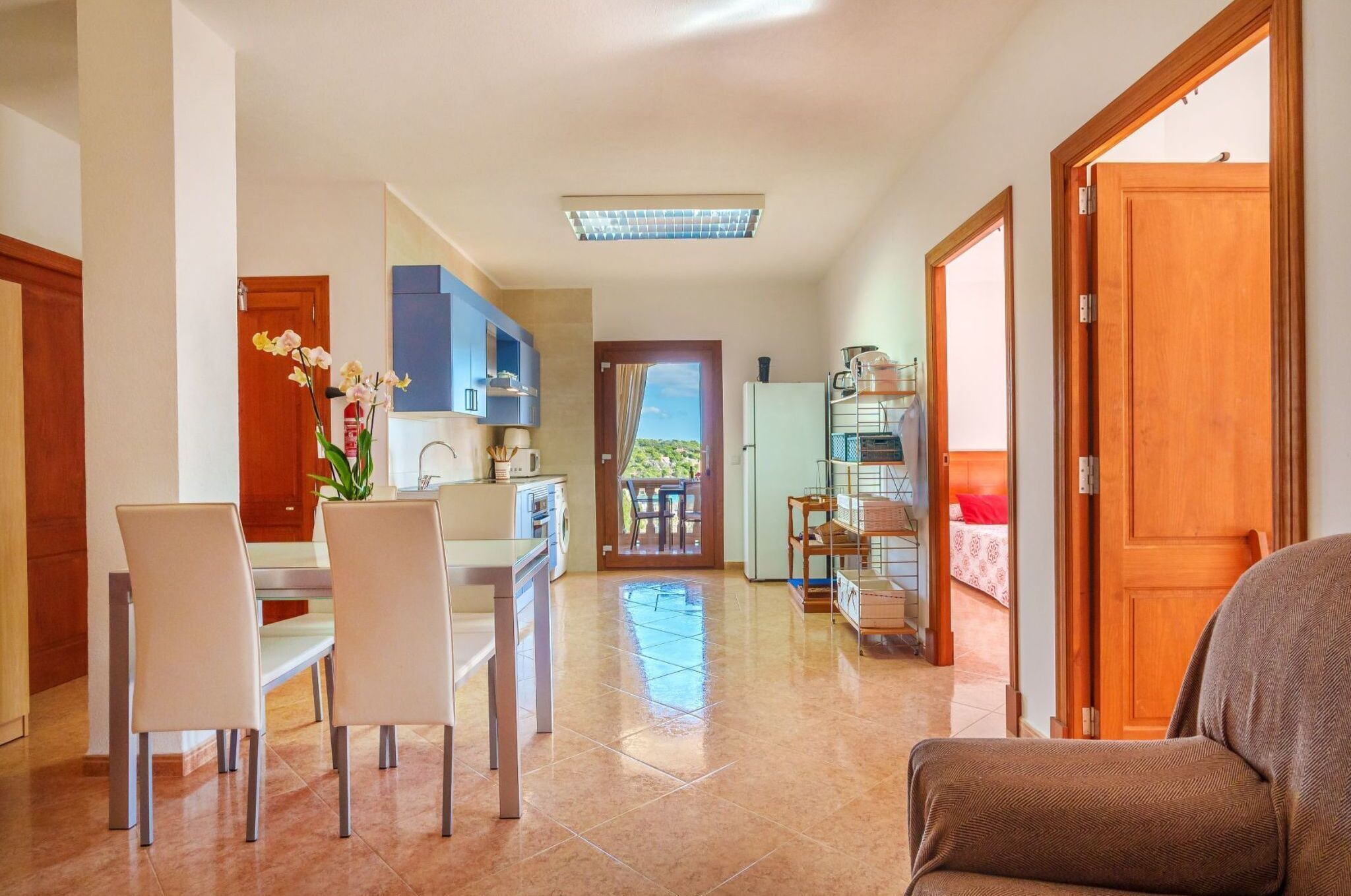 A modern kitchen with a dining area, a wooden door, and a view of the outside.