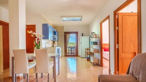 A modern kitchen with a dining area, a wooden door, and a view of the outside. - Vista Playa by Interhome (Llombards/C.Llombards/C.S'Almonia)