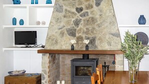 A stone fireplace with a modern TV, wooden furniture, and decorative items.