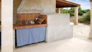 An outdoor kitchen with a sink, a drying rack, and a tiled backsplash.