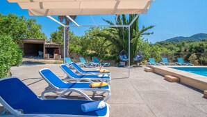 A poolside area with lounge chairs, a hanging chair, and a covered seating area. - Can Amagat by Interhome (Felanitx)