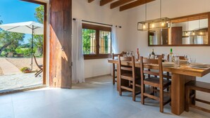 A dining area with wooden furniture, a large window, and a view of the outdoors. - Can Amagat by Interhome (Felanitx)