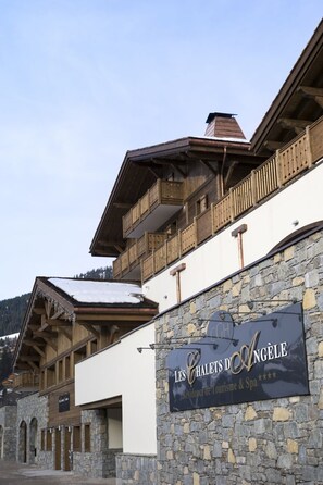 A hotel with a stone facade, wooden balconies, and a sign indicating it is a residence for tourism and spa.