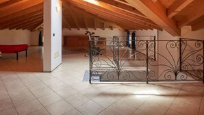 Un cuarto ático con un techo de madera alto, una reja metálica y un banco rojo.