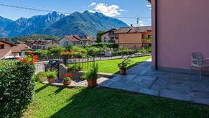 Un barrio residencial con casas, un jardín con plantas en macetas y montañas al fondo.