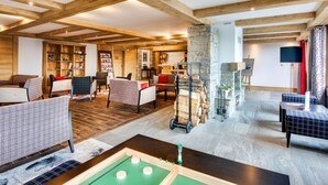 Un vaste espace intérieur agrémenté de poutres en bois, d’une table de billard, de sièges et d’une cheminée en pierre.