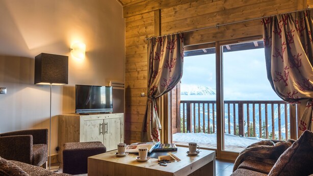 Une pièce confortable avec un plafond en bois, une télévision, un meuble, une table avec une tasse et une soucoupe, et un canapé.