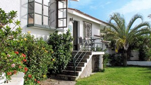 Una casa de dues plantes amb façana blanca, un balcó i una escala de pedra que condueix a l'entrada.