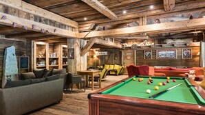 Un espace intérieur chaleureux et accueillant, avec une table de billard, des canapés et une cheminée.