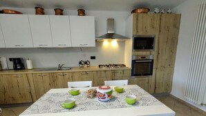 Une cuisine de taille réduite avec des meubles blancs, un plan de travail en bois et une table à manger avec des chaises.