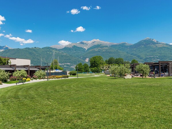 A grassy field with a mountain backdrop, a building with a modern design, and a clear sky. - Rodondello (CCO340) by Interhome (Colico)