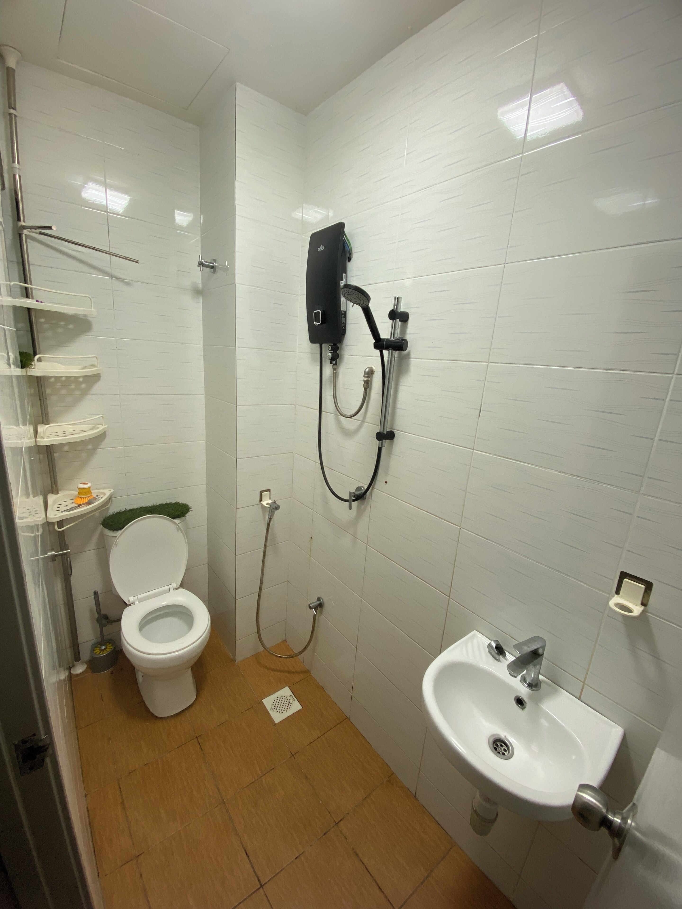 A small, tiled bathroom with a toilet, a shower unit, and a sink.