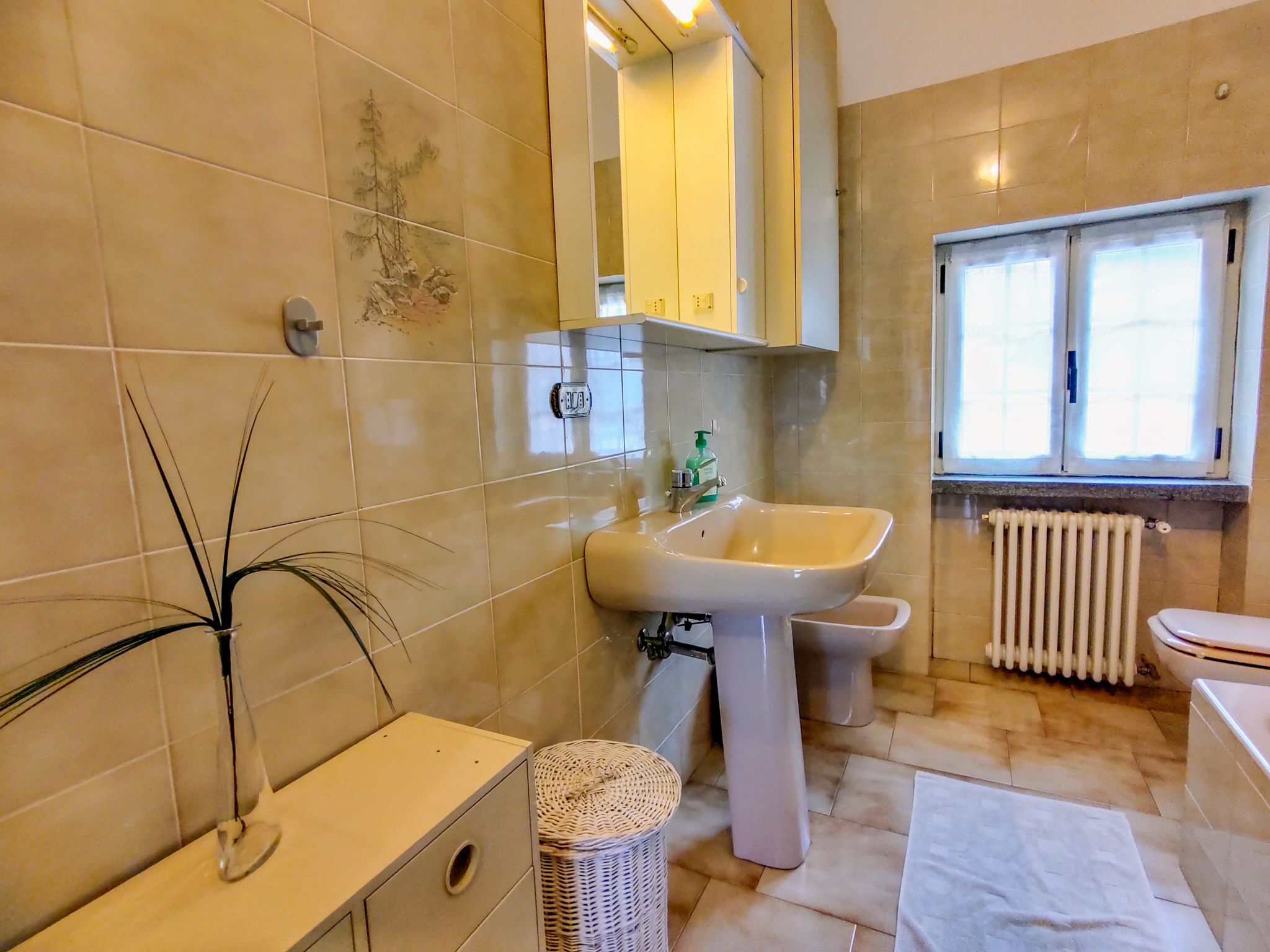 A bathroom with a sink, toilet, and a window.