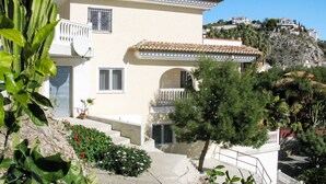 A two-story building with a tiled roof, a balcony, and a small garden area with plants and flowers. - Apartment Salz by Interhome (Salobreña)
