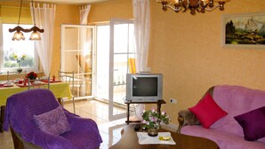 A living room with a purple armchair, a pink sofa, a wooden coffee table, and a television on a stand. - Apartment Salz by Interhome (Salobreña)