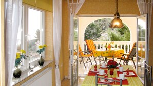 A dining area with a table set for two, a window with curtains, and a view of greenery outside. - Apartment Salz by Interhome (Salobreña)
