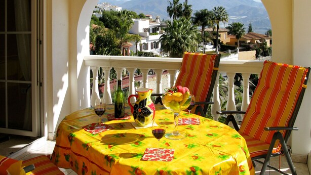 A balcony with a table set for two, a chair, and a view of a mountain range. - Apartment Salz by Interhome (Salobreña)