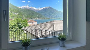 Une fenêtre donnant sur une montagne, un lac et des bâtiments.