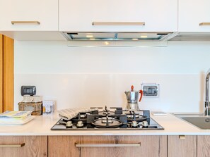 Une cuisine moderne équipée d’une cuisinière à gaz, d’une machine à café et d’un petit réfrigérateur.