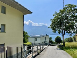 Une route étroite menant à un bâtiment d’où l’on a vue sur un lac et des montagnes.