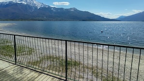Vista su un lago con montagne sullo sfondo, un pontile in legno e una ringhiera in metallo.