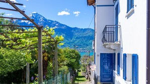 A narrow cobblestone street with a white building with blue shutters and a blue door. - Elisabetta (GLA116) by Interhome (Gera Lario)