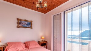 Une chambre à coucher comprenant un lit, une table de chevet, une lampe, un cadre photo et une porte-fenêtre coulissante donnant sur un balcon.