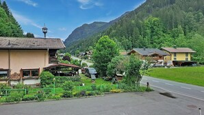 A mountain village with traditional buildings, a paved road, and lush greenery.