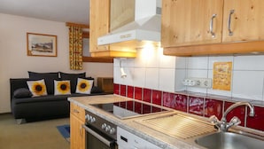 A compact kitchen with wooden cabinets, a built-in oven, a dishwasher, and a red-tiled backsplash.