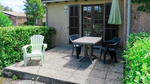 A patio with a table and chairs, a green chair, and a number 17 sign on a building.
