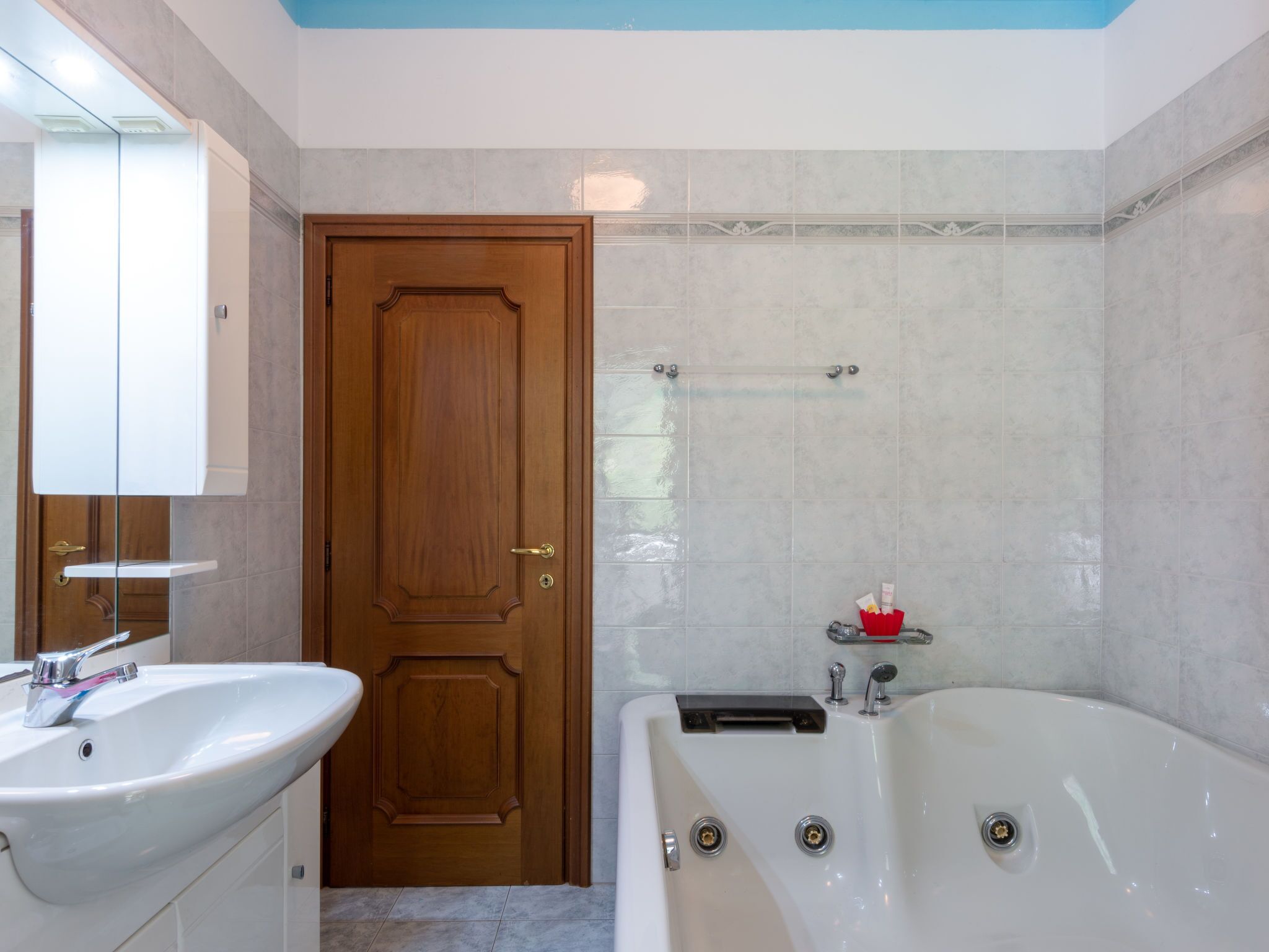 A bathroom with a wooden door, a white sink, and a bathtub.