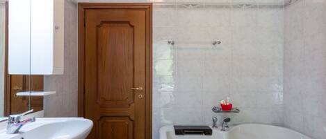 A bathroom with a wooden door, a white sink, and a bathtub.