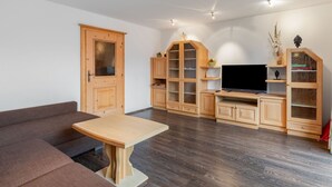A modern living room with a wooden sofa, a wooden dining table, and built-in wooden cabinets. - Prieslern by Interhome (Bramberg am Wildkogel)