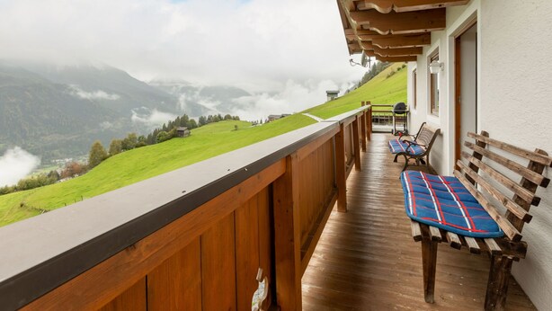 A wooden balcony with a view of a green hillside and mountains in the distance. - Prieslern by Interhome (Bramberg am Wildkogel)