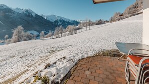 Une terrasse offrant une vue sur des montagnes enneigées et un ciel dégagé.
