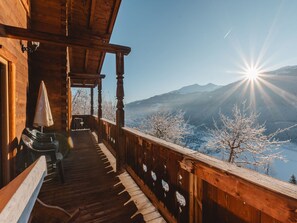 Ein Holzbalkon mit Blick auf schneebedeckte Bäume und Berge.