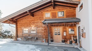 A wooden chalet with a covered entrance, outdoor seating, and a number 58 sign. - Geislhof by Interhome (Bramberg am Wildkogel)