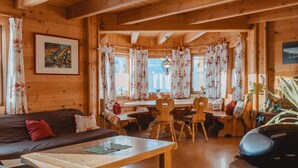 A cozy wooden cabin interior with a dining area, a sofa, and a coffee table. - Geislhof by Interhome (Bramberg am Wildkogel)