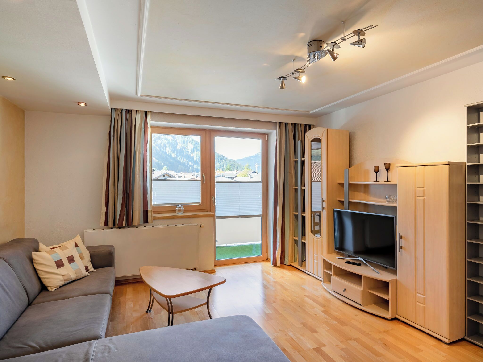 A modern living room with a sofa, a small table, a TV, and a wardrobe.