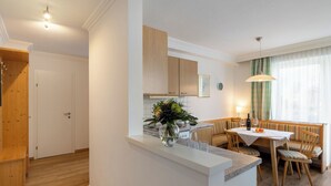 A modern kitchen with white cabinets, a wooden countertop, and a dining area with a table and chairs. - Weberbauer by Interhome (Mittersill)