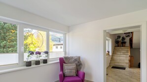 A corner room with a purple armchair, a window with blinds, and a view of a house and trees. - Weberbauer by Interhome (Mittersill)
