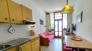 A compact kitchen with wooden cabinets, a coffee machine, and a dining area with a table and chairs.