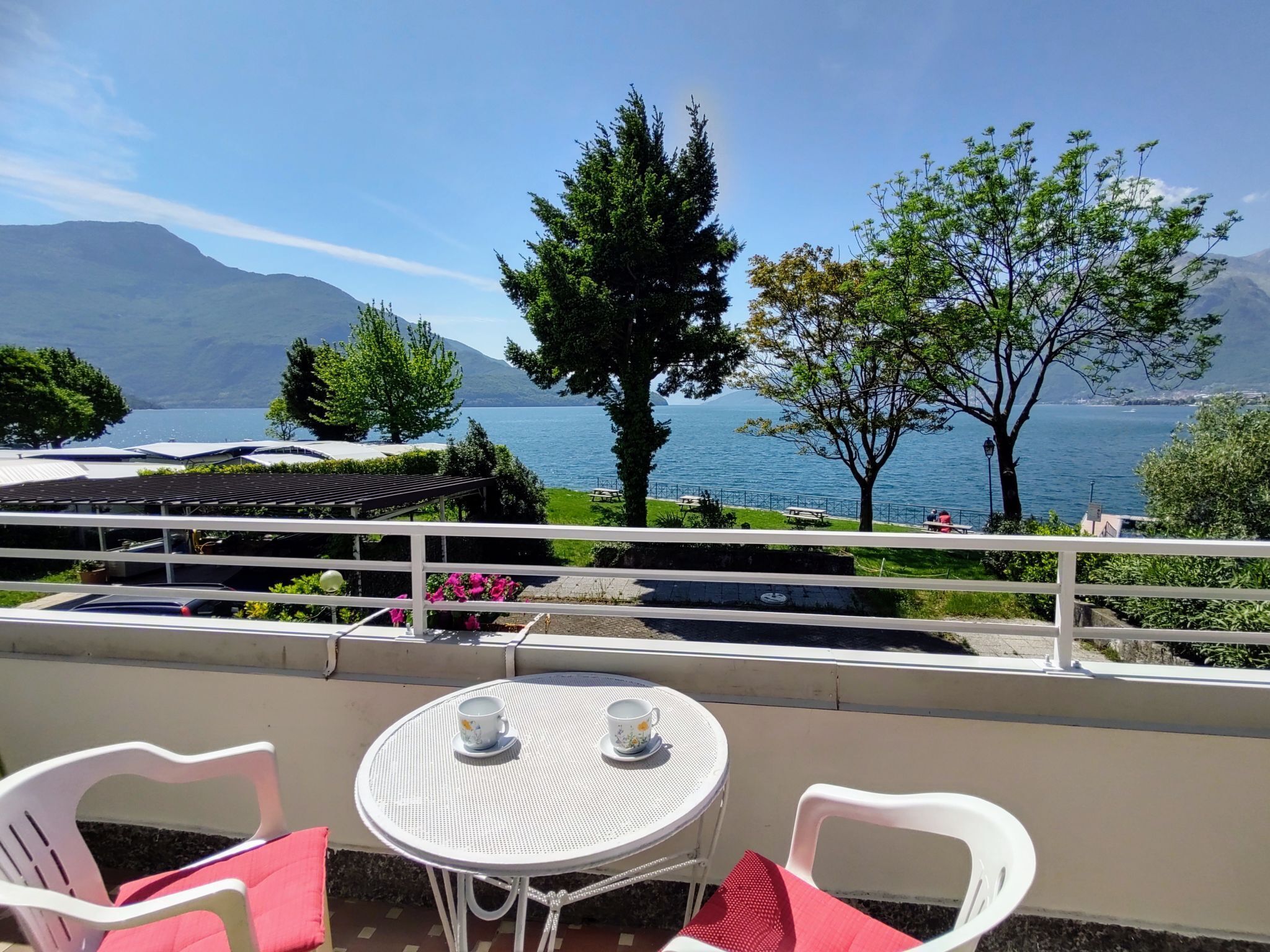Un balcon avec une table et des chaises donnant sur un lac et des montagnes.