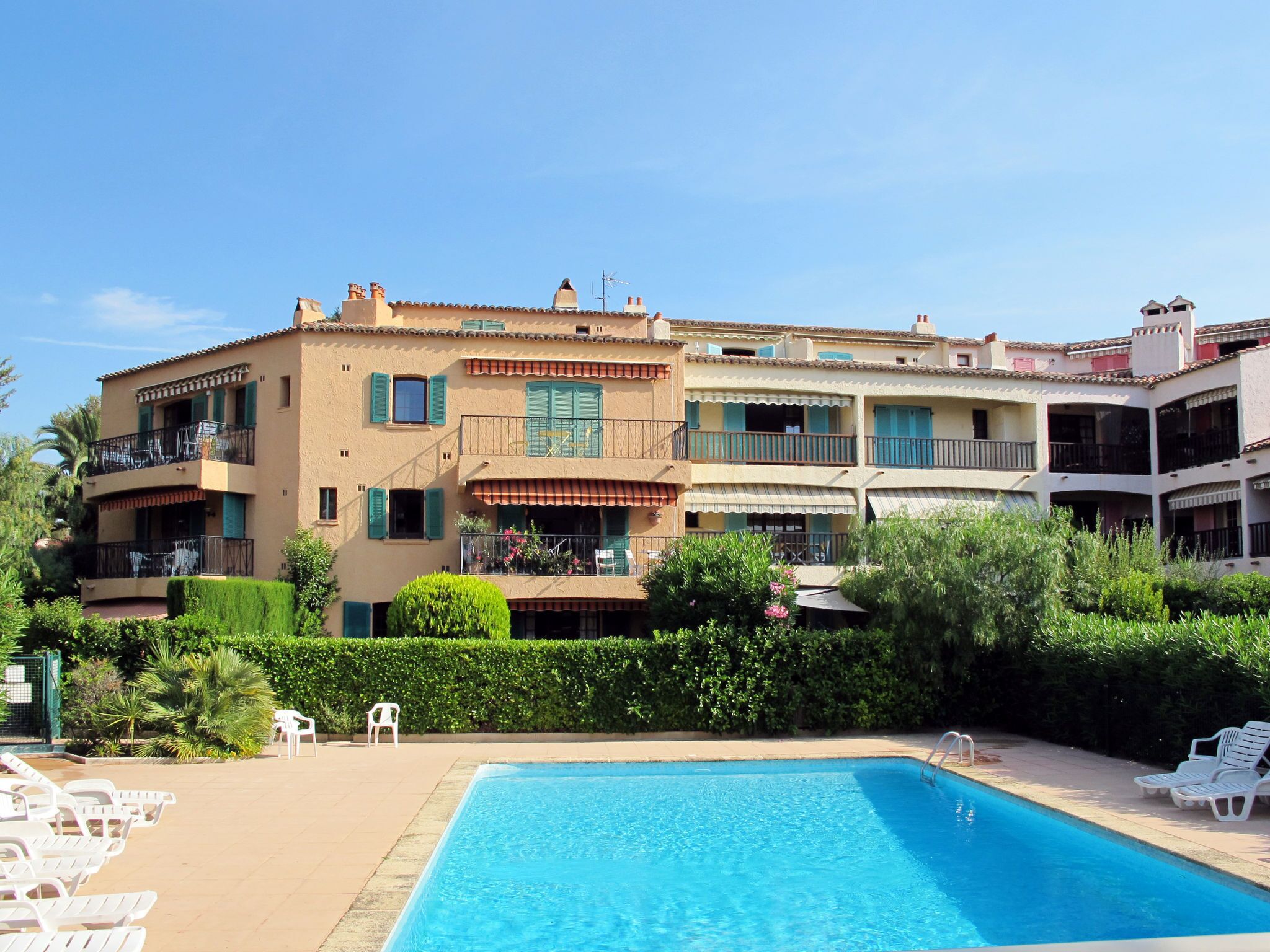 A hotel with a swimming pool, multiple balconies, and a well-maintained garden.
