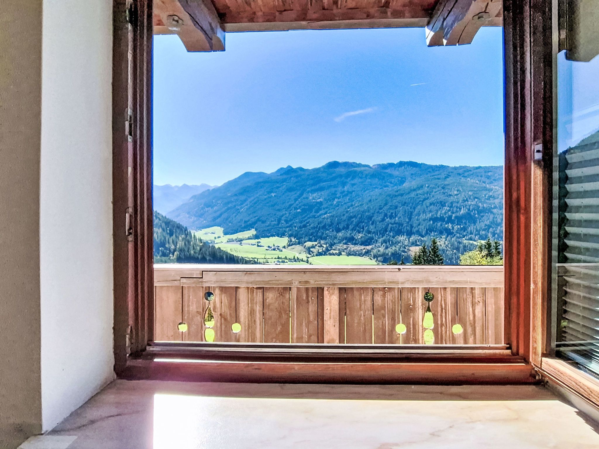 Un balcon doté d’une balustrade en bois et offrant une vue sur un paysage montagneux.